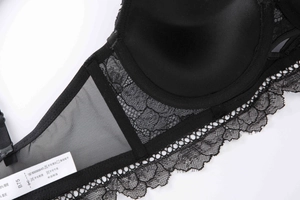 Detail view of black lace bra wing and mesh fabric showing size tag B75 and quality stitching