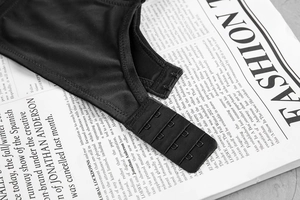Close-up of black seamless bra featuring triple hook-and-eye back closure on newspaper