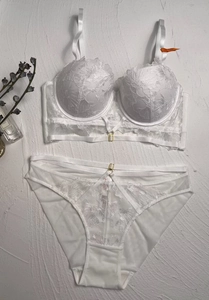 Detailed flat lay of white lace lingerie set with floral embroidery and buckle detail