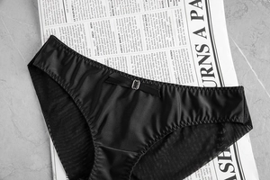 Detail of black satin and mesh panties with silk bow and silver metallic buckle