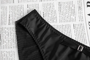 Detail of smooth satin black lingerie with wavy edges, ribbon bow and metal adjuster