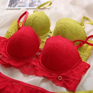 Detailed view of floral lace embroidery and gold ring accents on red and green bras