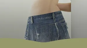 Detail view of denim skirt with distressed frayed edges and high-waisted back pocket design