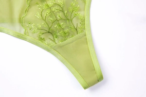 Detailed macro view of lime green floral lace embroidery on sheer mesh fabric