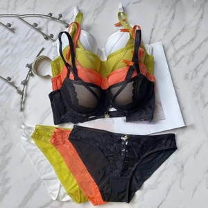 Completi intimi in pizzo nero, arancione, lime e bianco su sfondo di marmo elegante