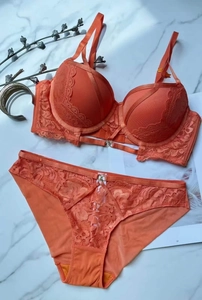 Dettaglio di un set di lingerie in pizzo arancione vivace su sfondo di marmo raffinato