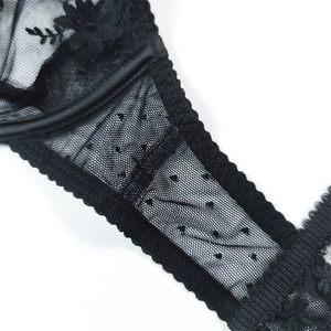 Detailed close-up of black lace bra featuring floral embroidery and polka dot mesh fabric