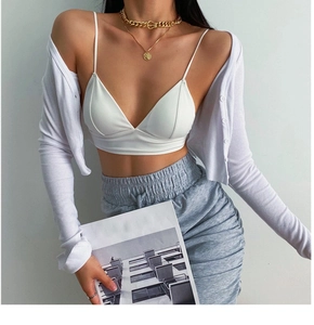 Detail of white rib-knit cardigan and seamless V-neck bralette with gold chain necklaces