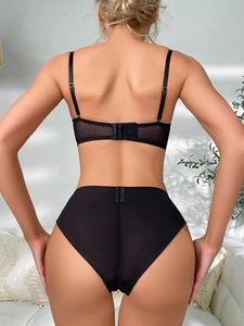 Détail du dos du soutien-gorge en maille noire avec agrafes réglables et culotte haute assortie