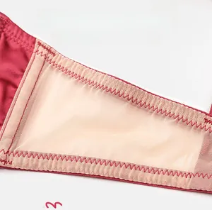 Macro detail of breathable mesh side wing on wine red satin bra for smoothing effect