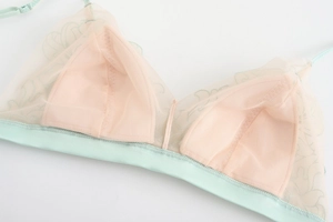 Detail view of mint green mesh bra showing fine embroidery and breathable fabric texture