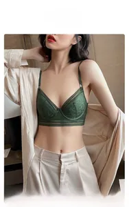 Detail of elegant dark green lace bra with wide hem worn under a champagne satin cardigan