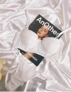 Flat lay of white lace 1/2 cup bra and thong set on satin fabric with a fashion magazine