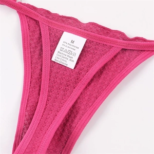 Détail d'un string rose rouge avec texture gaufrée, bordure en dentelle et étiquette taille M