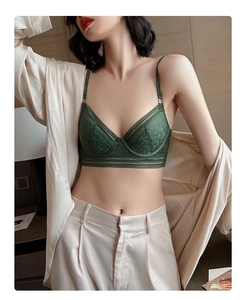 Detailed close-up of dark green lace bra set with silk cardigan in a cozy home setting