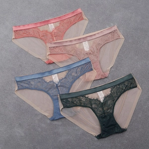 Vue à plat de quatre culottes en dentelle rose, bleue et verte avec fond coton