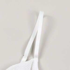 Detail of white lace bra strap with adjustable silver metal buckle and fabric texture