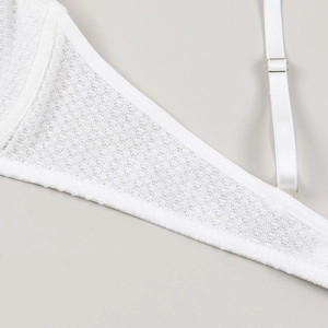 Close-up of white lace mesh fabric with adjustable thin shoulder straps and metal buckle