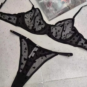 Détail à plat d'un ensemble de lingerie en dentelle noire avec motif cœurs sur marbre
