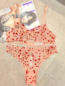 Detailed flat lay of pink mesh lace lingerie set with red heart print and ruffle trim