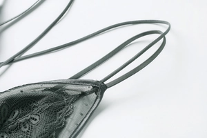 Dettaglio del reggiseno in pizzo grigio-verde con rete floreale e cuciture in raso