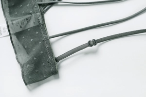 Dettaglio macro del reggiseno in pizzo grigio scuro con rete a pois e spalline sottili
