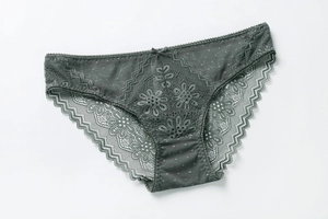 Dettaglio di slip in pizzo scuro con ricami floreali e un piccolo fiocco centrale