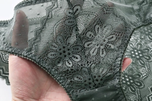 Dettaglio in pizzo floreale verde scuro con bordi smerlati e tessuto a rete sottile
