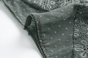 Dettaglio ravvicinato di lingerie in pizzo verde scuro con ricami floreali e tulle