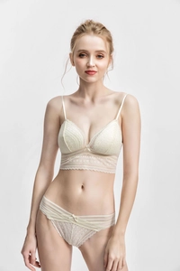 Detail eines eleganten elfenbeinfarbenen Spitzen-Dessous-Sets mit Schleife und floralem Muster