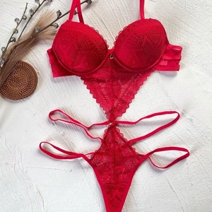 Flat lay close-up of red lace bodysuit with intricate floral patterns and cutout details