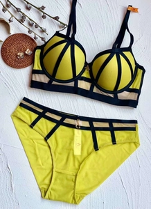 Detailed view of neon yellow lace bra set with black cage straps and gold G-pendant