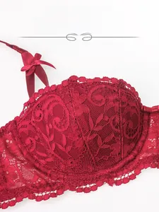 Détail macro du soutien-gorge en dentelle rouge vin avec textures florales et noeud satin