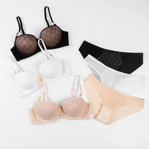 Flat lay of quilted lingerie sets in black, white and nude colors with gold ring details