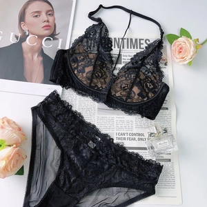 Flat lay of black lace lingerie set with floral embroidery on a vintage newspaper background
