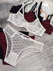 Dettaglio di completi intimi in pizzo bianco, bordeaux e nero con paillettes dorate