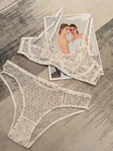 Dettaglio di un set di lingerie in rete bianca con ricamo a pois dorati e pizzo