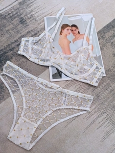 Set di lingerie in rete bianca a pois dorati steso con una rivista di moda di lusso