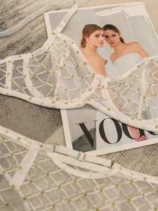 Dettaglio del set di lingerie in rete bianca con pois dorati su rivista Vogue
