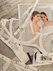 Dettaglio del reggiseno in mesh bianco trasparente con ricamo a pois dorati e ferretto