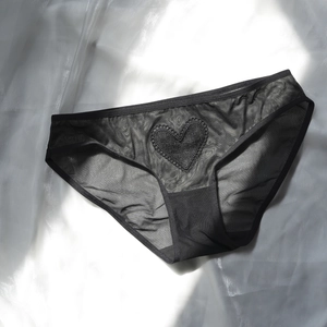 Detailed close-up of heart-shaped lace embroidery on black sheer mesh women underwear