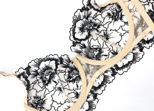 Detail of floral black embroidery on white semi-transparent mesh lace lingerie fabric