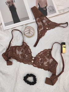 Flat lay of brown sheer floral lace lingerie set with tiny buttons on knit background