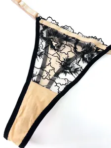 Detailed view of floral lace embroidery and adjustable side straps on black thong