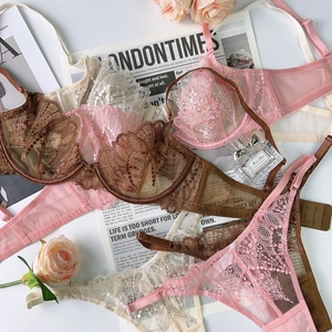 Detailed flat lay of pink lace bra and panty set with vintage newspaper and roses