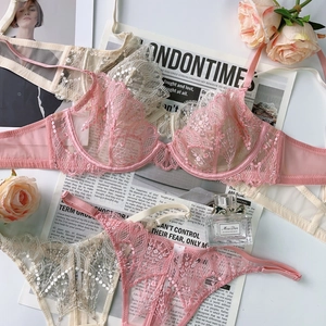 Flat lay of delicate floral lace lingerie sets with embroidery in grey pink and off-white