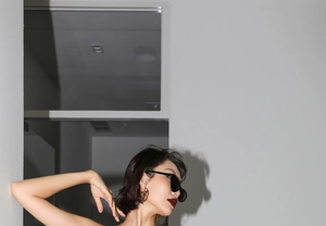 Gros plan de lunettes de soleil œil-de-chat noires et créoles dorées sur un mannequin