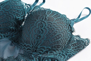 Detailed close-up of dark teal floral lace and delicate eyelash trim on a slim bodysuit