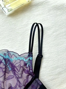 Détail de lingerie en dentelle violette avec broderie florale bleue et bretelles doubles