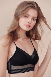 Détail d'une bralette noire en dentelle à col V avec tulle à pois et fines bretelles